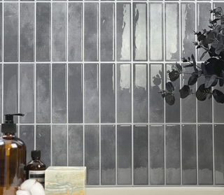 Azulejos autoadhesivos Ceniza Volcánica estilo columna instalados en pared de baño moderno.