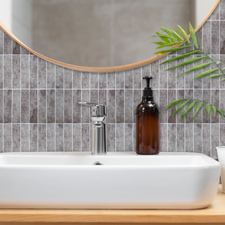 Azulejos autoadhesivos Ceniza Volcánica estilo columna instalados en pared de baño moderno.