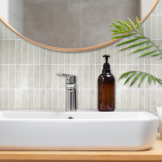 Azulejos autoadhesivos Desierto Crema estilo columna instalados en pared de baño moderno.