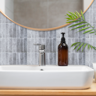 Azulejos autoadhesivos Gris Ártico estilo columna instalados en pared de baño moderno.