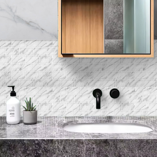 Azulejos autoadhesivos Mármol Carrara estilo ladrillo instalados en pared de baño moderno.